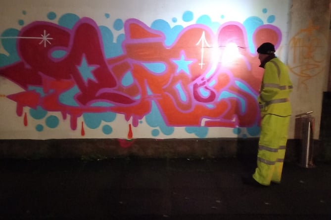 A worker cleans up the graffiti at the bus station