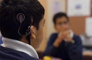 pupil with hearing aid watching sign language.