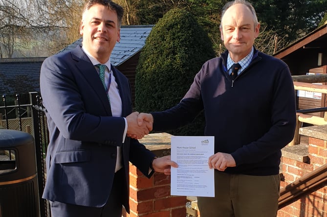 Head of boarding Fred Pennell and headteacher Jonathan Hetherington holding the Ofsted report in front of the school entrance
