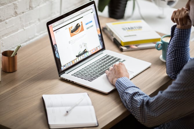 A photo of a man working at a laptop.