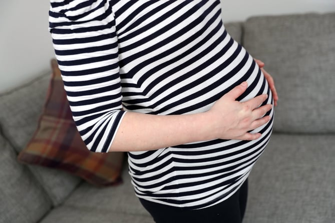 A pregnant woman holds her stomach.
