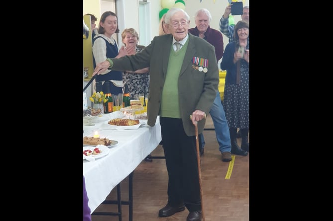 John Gwynne cuts his 101st birthday cake, surrounded by family and friends