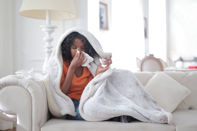 Woman in blanket suffering from cold, flu or allergy
