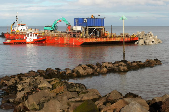 Coastal defences - A barge offloads rock armour during the first emergency repairs