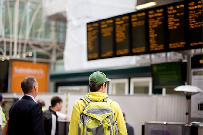 Passengers checking a departures board at a large railway station