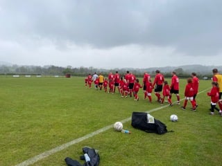 Talgarth Town Veterans being lead out on to the pitch by Talgarth Junior Girls team.
