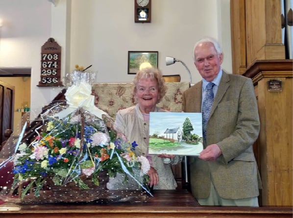 Mr and Mrs Beaumont pictured with their gifts of a flower arrangement and painting of the chapel.