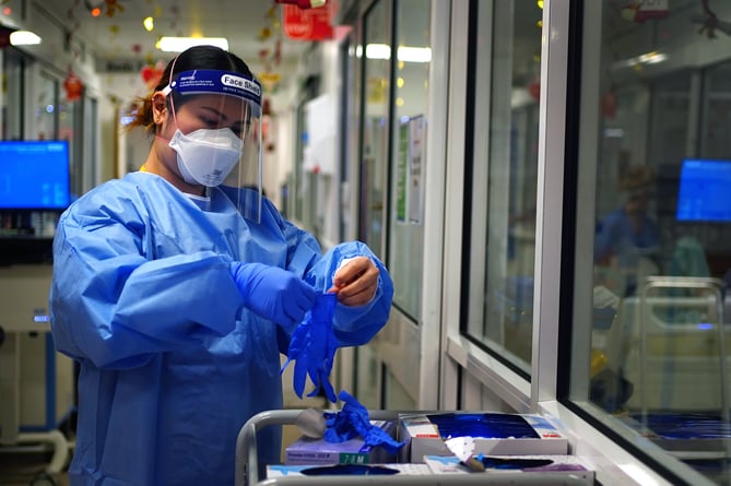 File photo dated 21/12/2021 of a nurse puts on PPE in a ward for Covid patients at King's College Hospital, in south east London. The Government has been told to "get a grip" of personal protective equipment (PPE) stocks and contracts, as it was disclosed more than half of suppliers who provided items through the VIP fast-track lane provided stock that was not suitable for use on the front line. Issue date: Wednesday March 30, 2022.