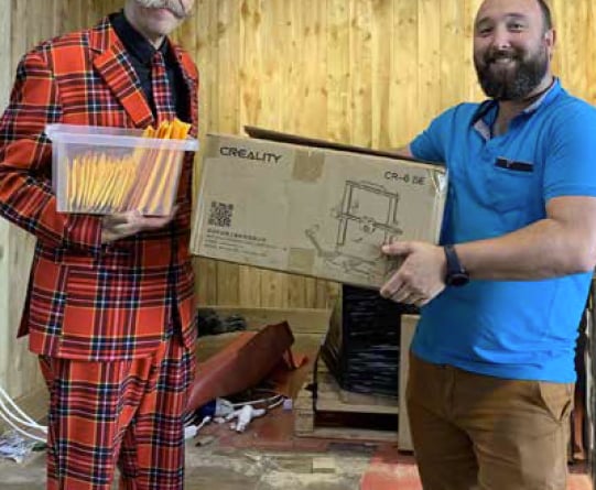 Stuart Morrison, left, gives a 3D printer to Paul Jones.